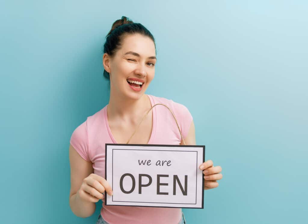 business owner holding the sign for the reopening